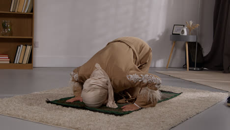 Muslimische-Frau-Mit-Hijab-Zu-Hause-Beten-Kniend-Auf-Gebetsmatte-5